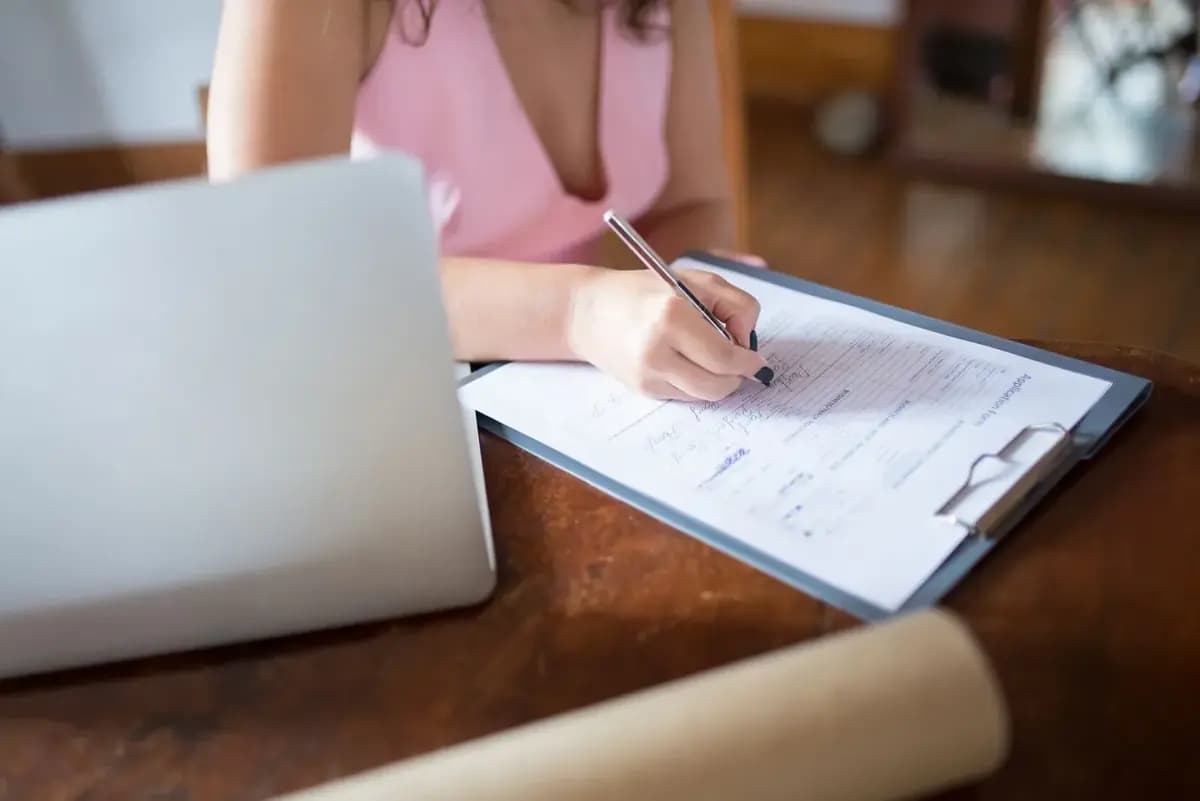 Student filling in an application form next to a laptop
