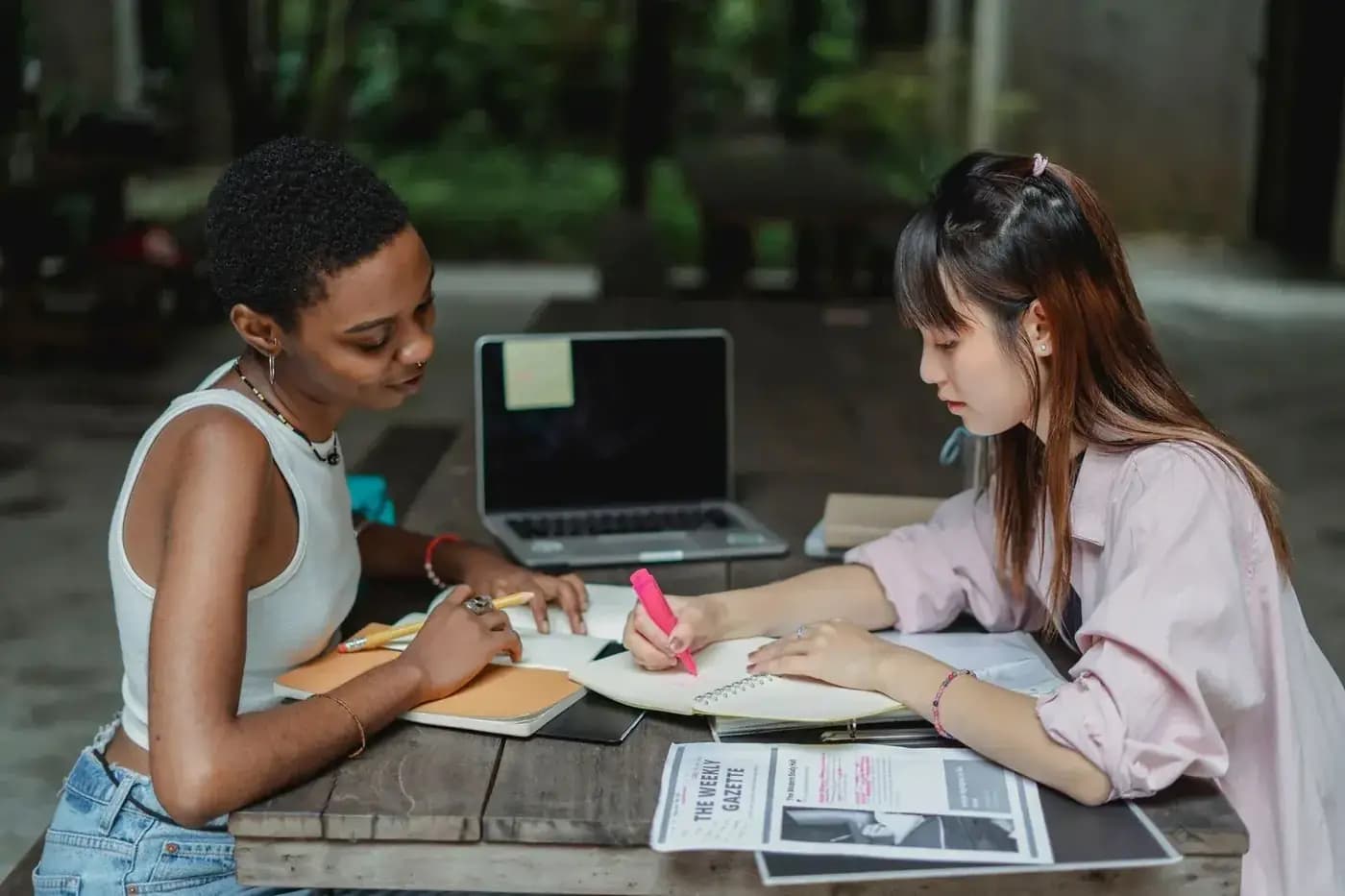 Two students planning their application with notebooks and a laptop